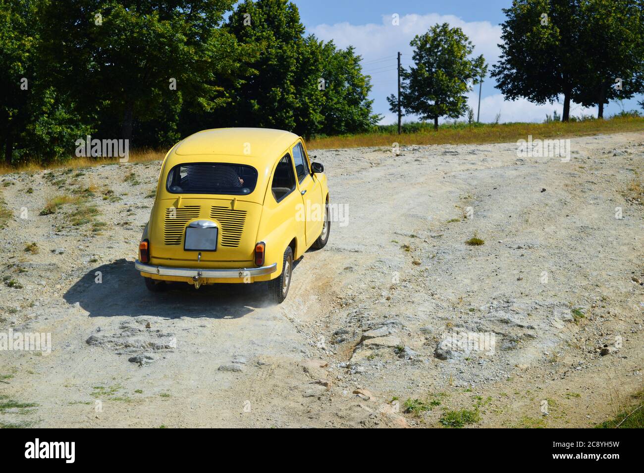 This photo was taken in the summer of 2018 in North Macedonia. A local man drives his small car on a bumpy road. Stock Photo
