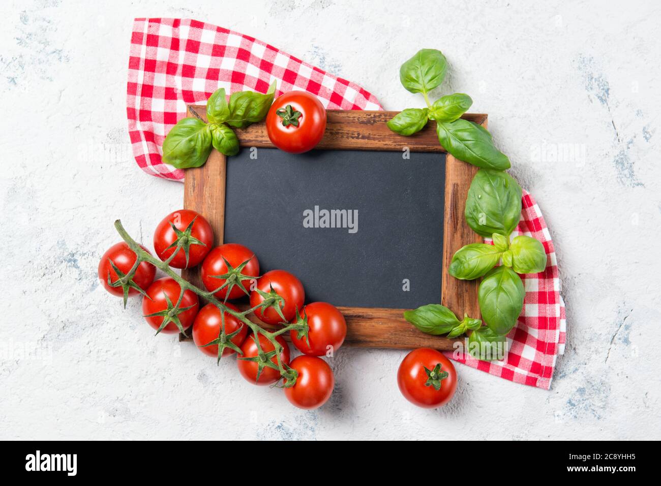 Ripe cherry tomatoes and fresh basil leaves on stone table with ...