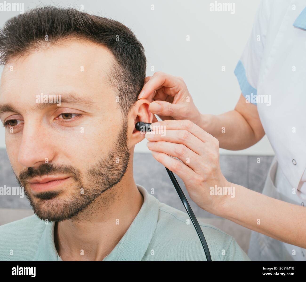 Mixed race man having a hearing test with special medical equipment. Impedance audiometry, tympanometry in a hearing center Stock Photo