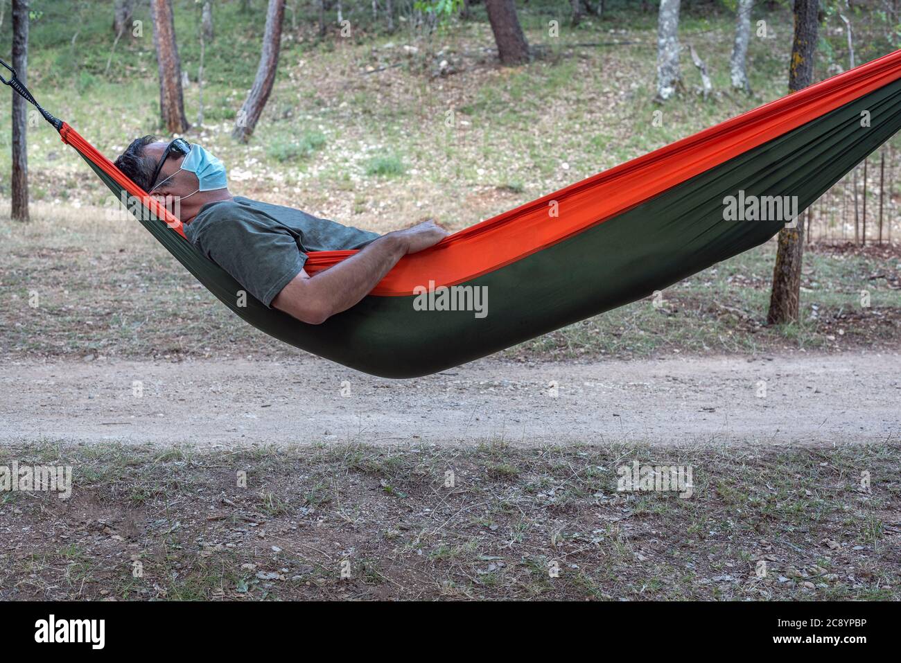 Man lying in a hammock with his mask on Stock Photo