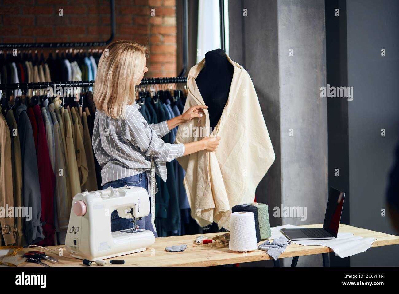 young dressmaker creating a garment, close up back view photo. job, professiona, occupation