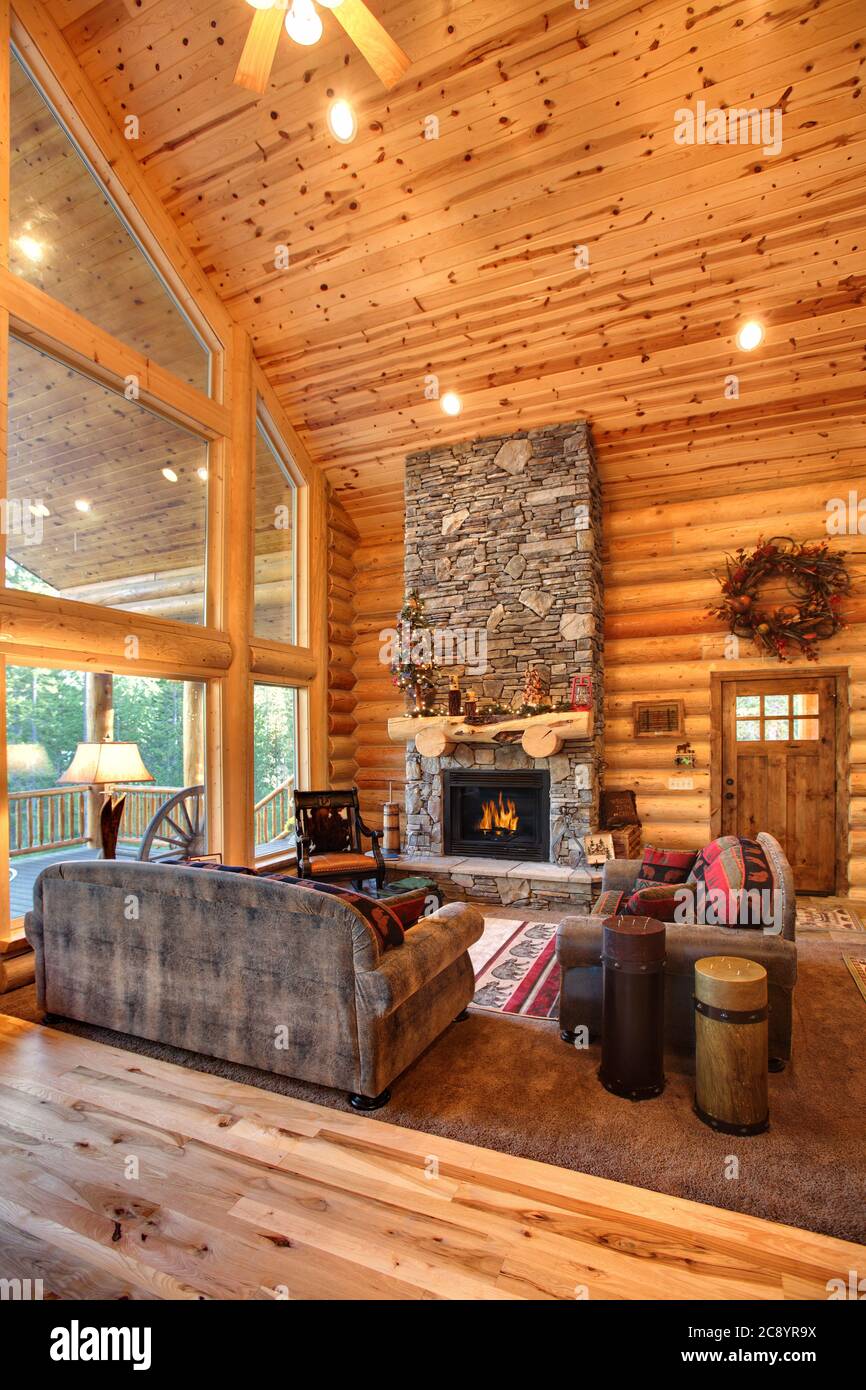 A luxurious living room, with a fireplace and comfortable furnishings, in a modern log cabin in the mountains. Stock Photo