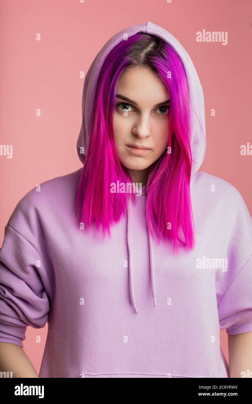 confident serious street girl with straight violet hair in hoody. close up portrait.studio shot. isolated pink background Stock Photo
