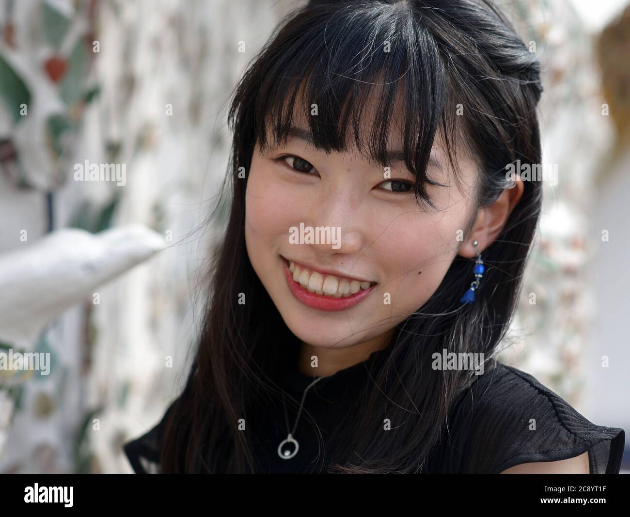 Pretty Japanese female tourist smiles for the camera at Bangkok's famous Wat Arun Temple. Stock Photo