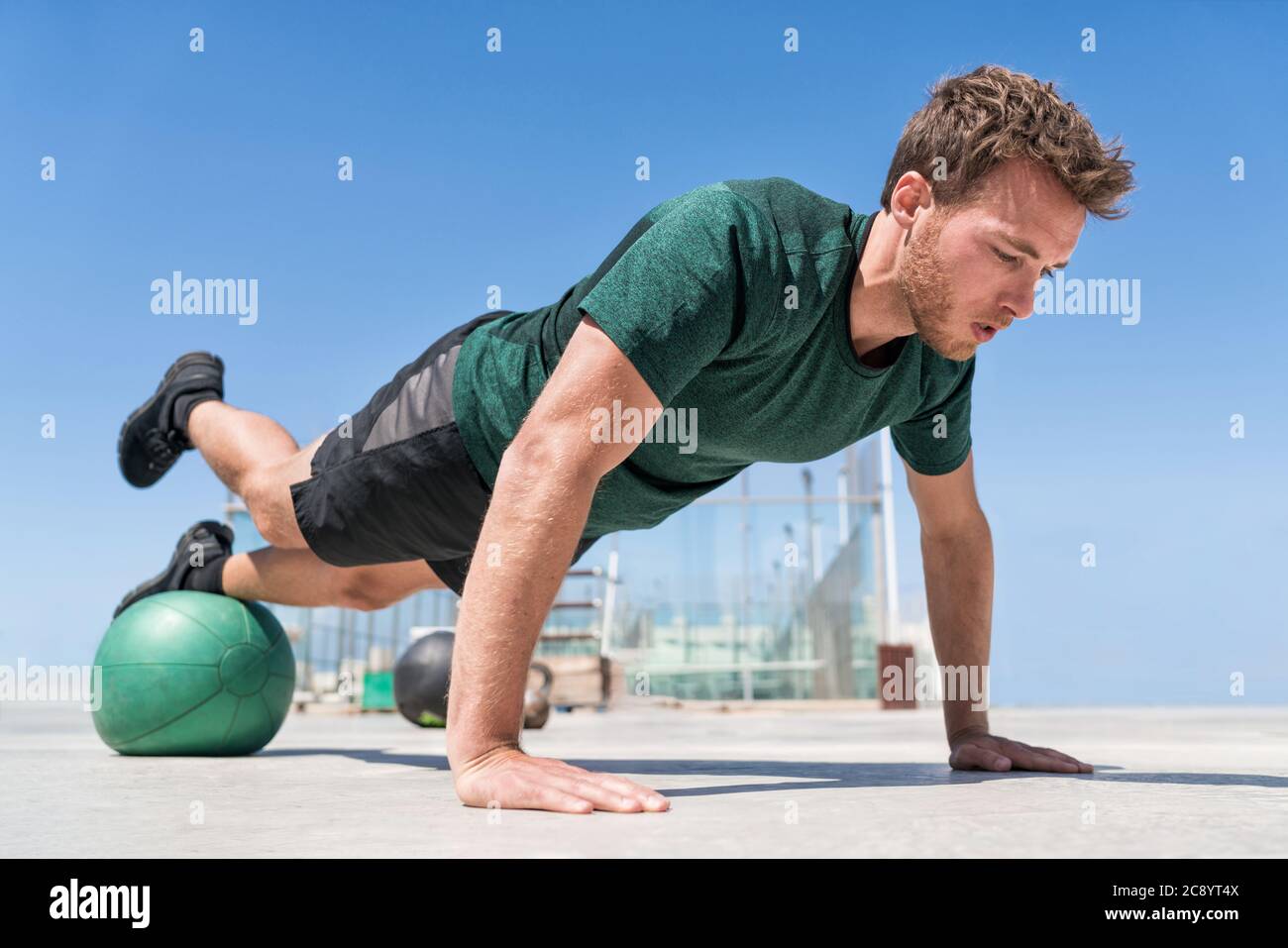 Man doing pushups balancing on medicine ball Stock Photo