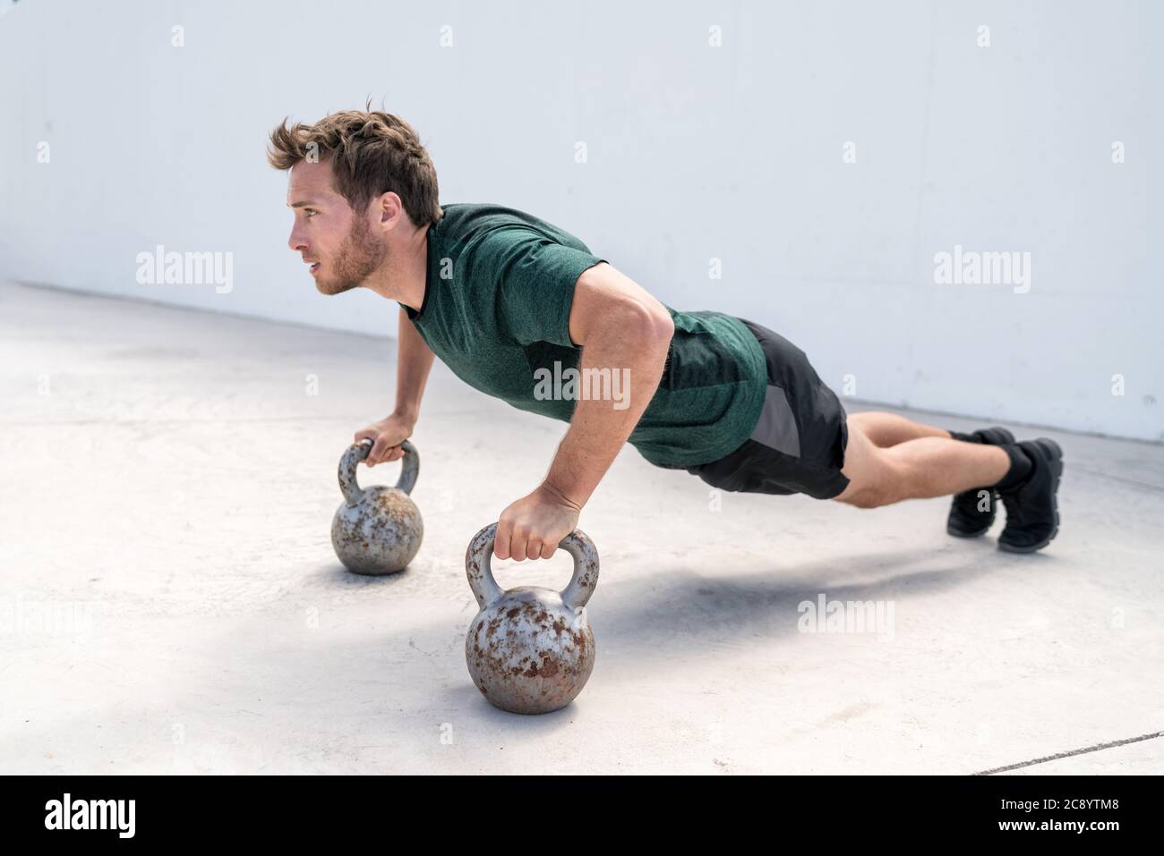 Fitness man doing push-ups holding on kettlebells Stock Photo