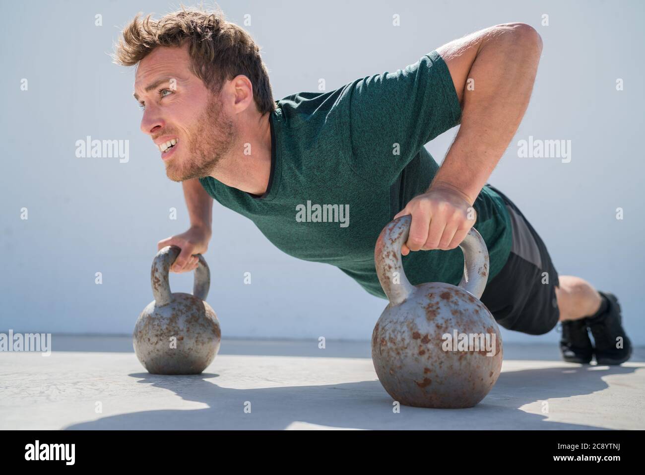 Fitness gym pushups man working out on kettlebells Stock Photo