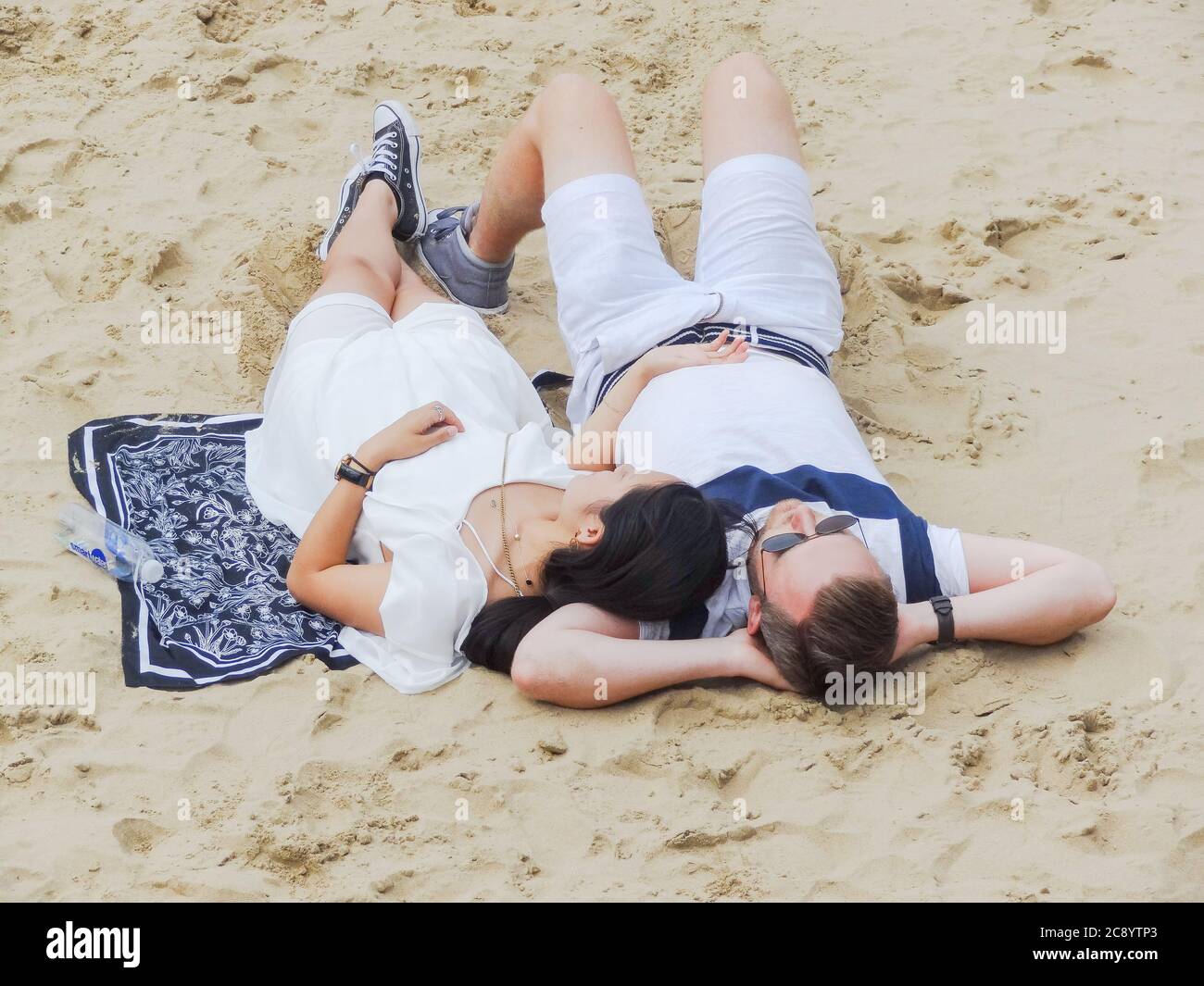 A young couple relaxing on the beach next to the River Thames on on London's Southbank Stock Photo