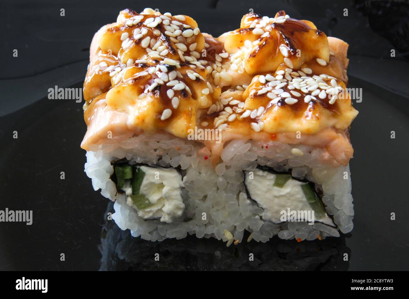 Japanese sushi food on the black plate. Baked warm rolls with tuna