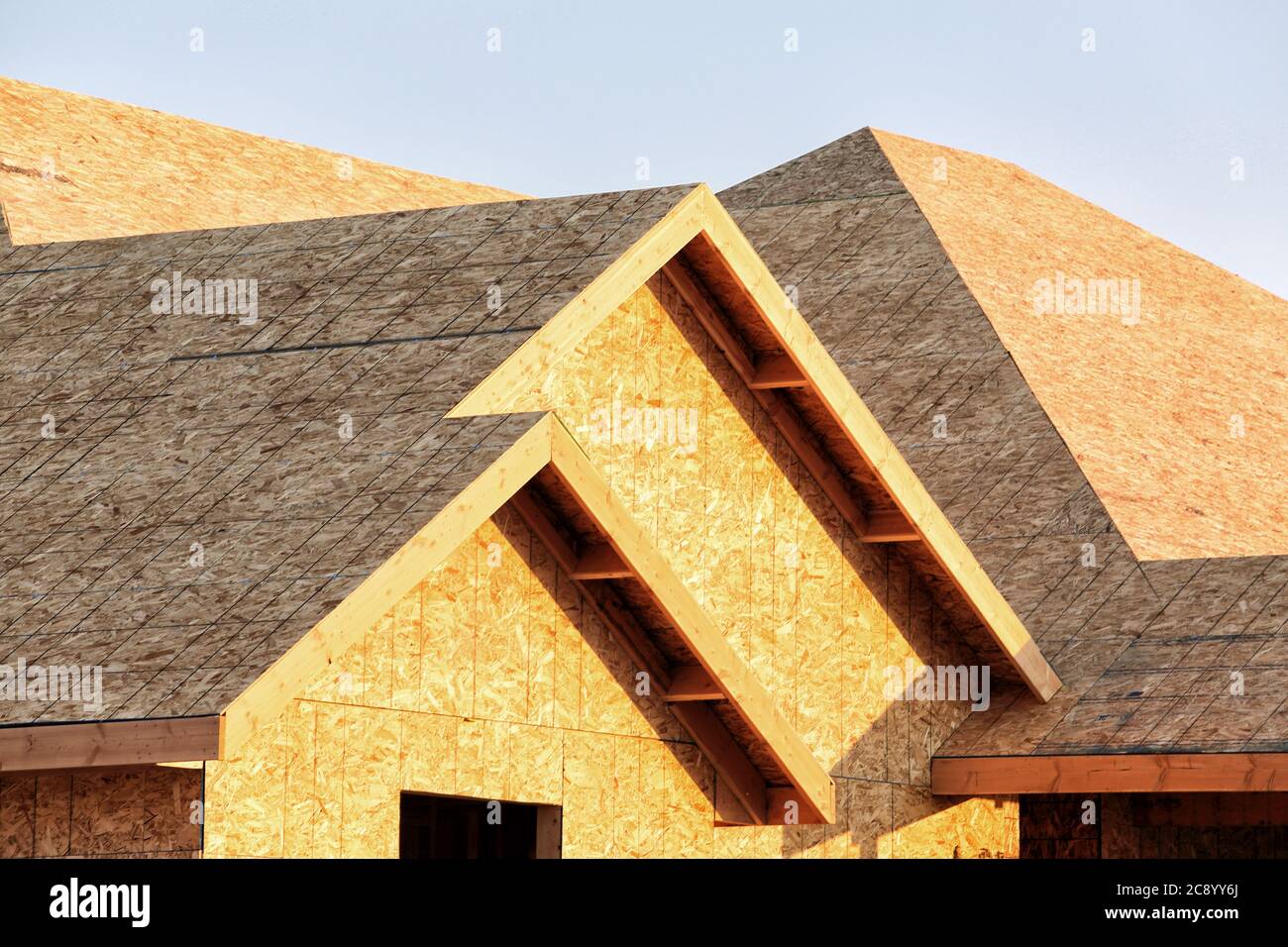 A stickbuilt residential building, with fir roof trusses and oriented strand board sheathing, under construction. Stock Photo