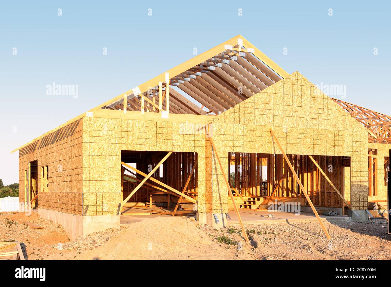 A stickbuilt residential building, with fir roof trusses and oriented strand board sheathing, under construction. Stock Photo