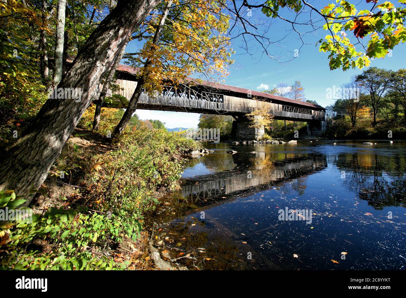 The Blair Covered Bridge in Campton, NH over the Pemigewasset River, was orginally built in 1869 in a long truss with arches design. Stock Photo