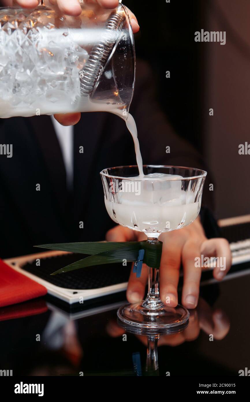 Detail of bartender's hand working in the bar with his shaker and pouring a  cocktail in the glass - a Royalty Free Stock Photo from Photocase