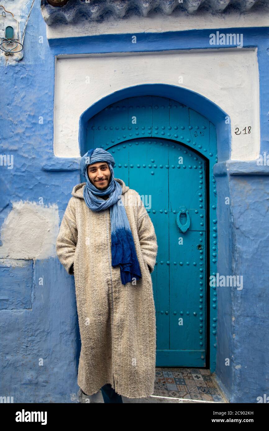 A young Berber with blue turban sells his wares in the city of