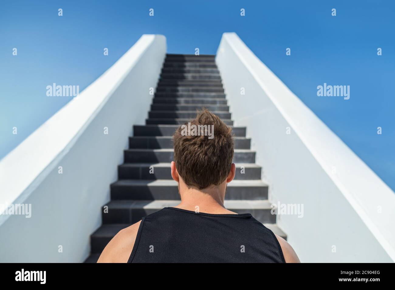 Fitness man looking ahead at stairs climbing challenge. Runner going up running staircase for cardio goal doing weight loss choice in healthy Stock Photo