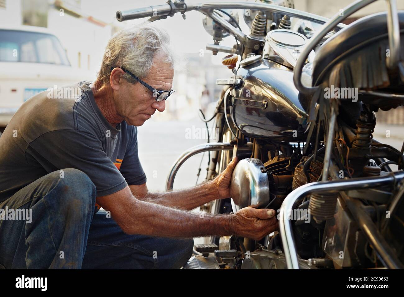 Senior Man Examining His Motorcycle And Fixing Engine Stock Photo