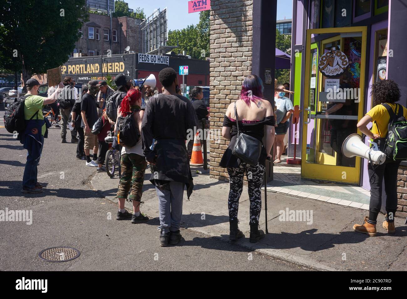 A group of BLM protesters demonstrate outside the Voodoo Donuts shop as they march along the 3rd Ave towards the federal courthouse in Portland, Oregon. Stock Photo