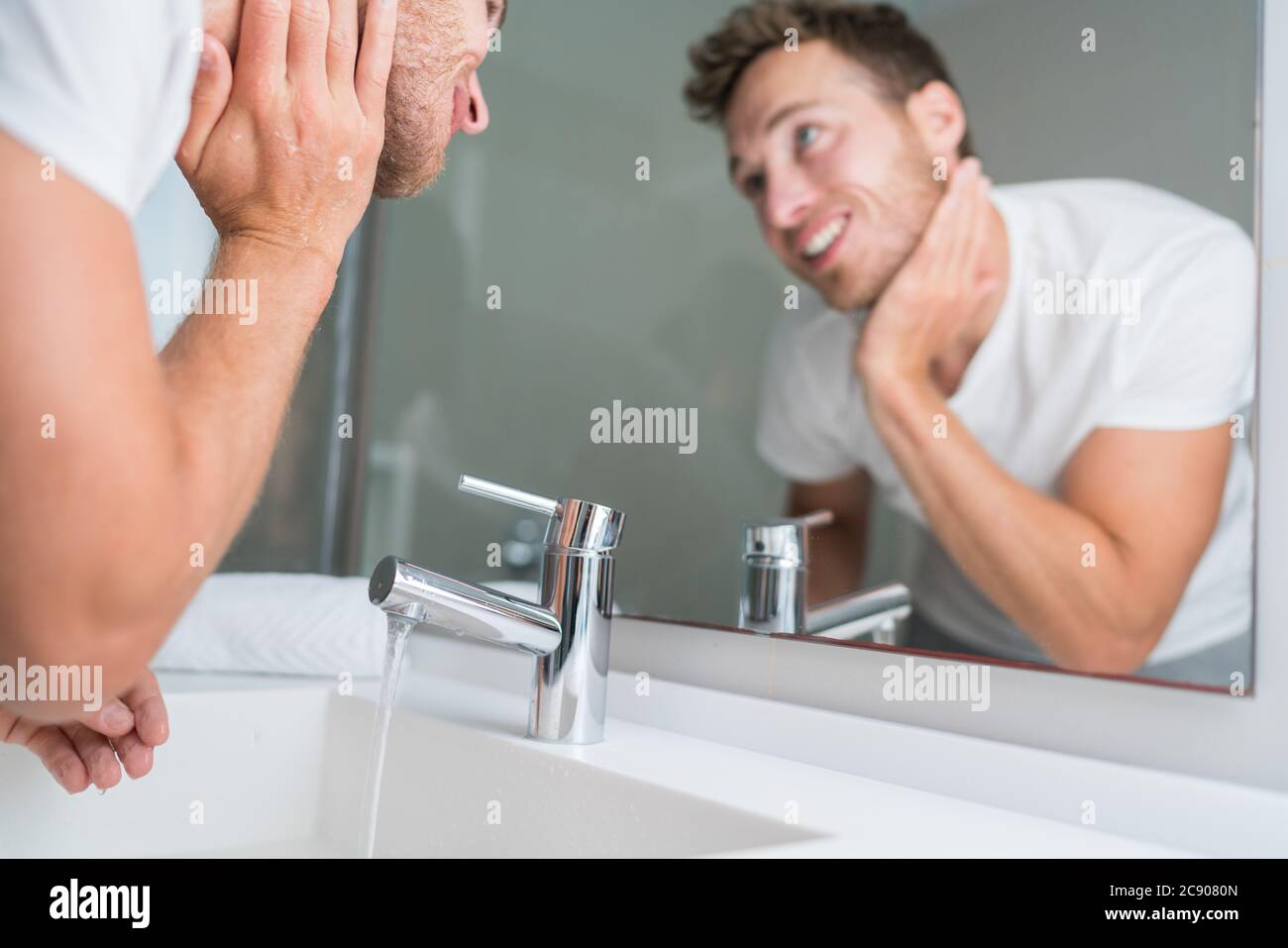 Man washing face in sink in bathroom rinsing after shaving. Home lifestyle copyspace Stock Photo