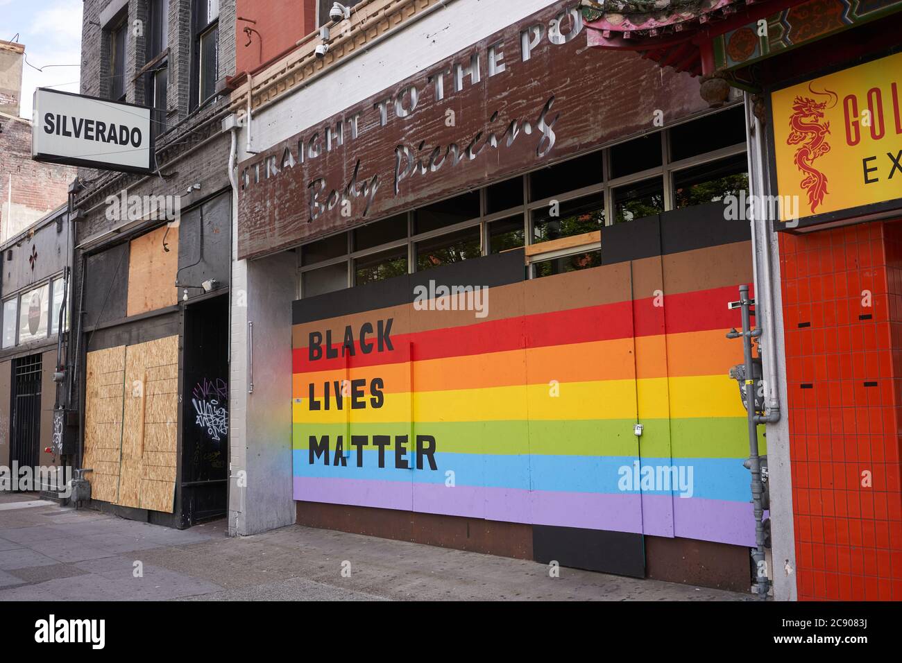 Black Lives Matter sign on the Rainbow Flag seen at the boarded-up storefront of a local business in downtown Portland, Ore., on Saturday, 7/11/2020. Stock Photo