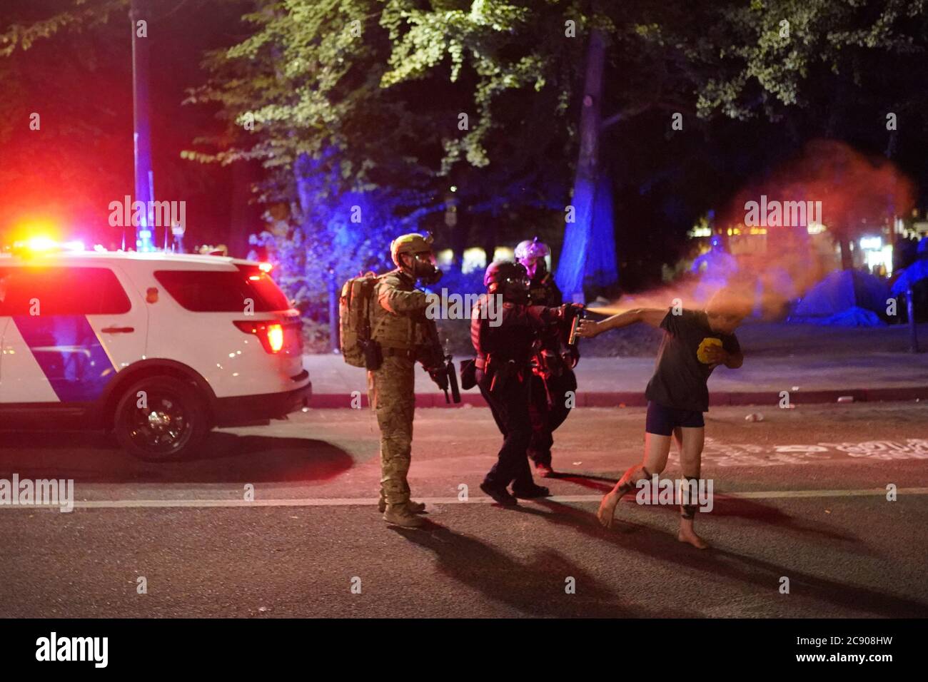 Portland, Oregon, USA. 26th July, 2020. Federal officers pepper spray a protester after dispersing a crowd in front of the Mark O. Hatfield U.S. Courthouse in Portland, Ore., on Sunday. Credit: Nathan Howard/ZUMA Wire/Alamy Live News Stock Photo