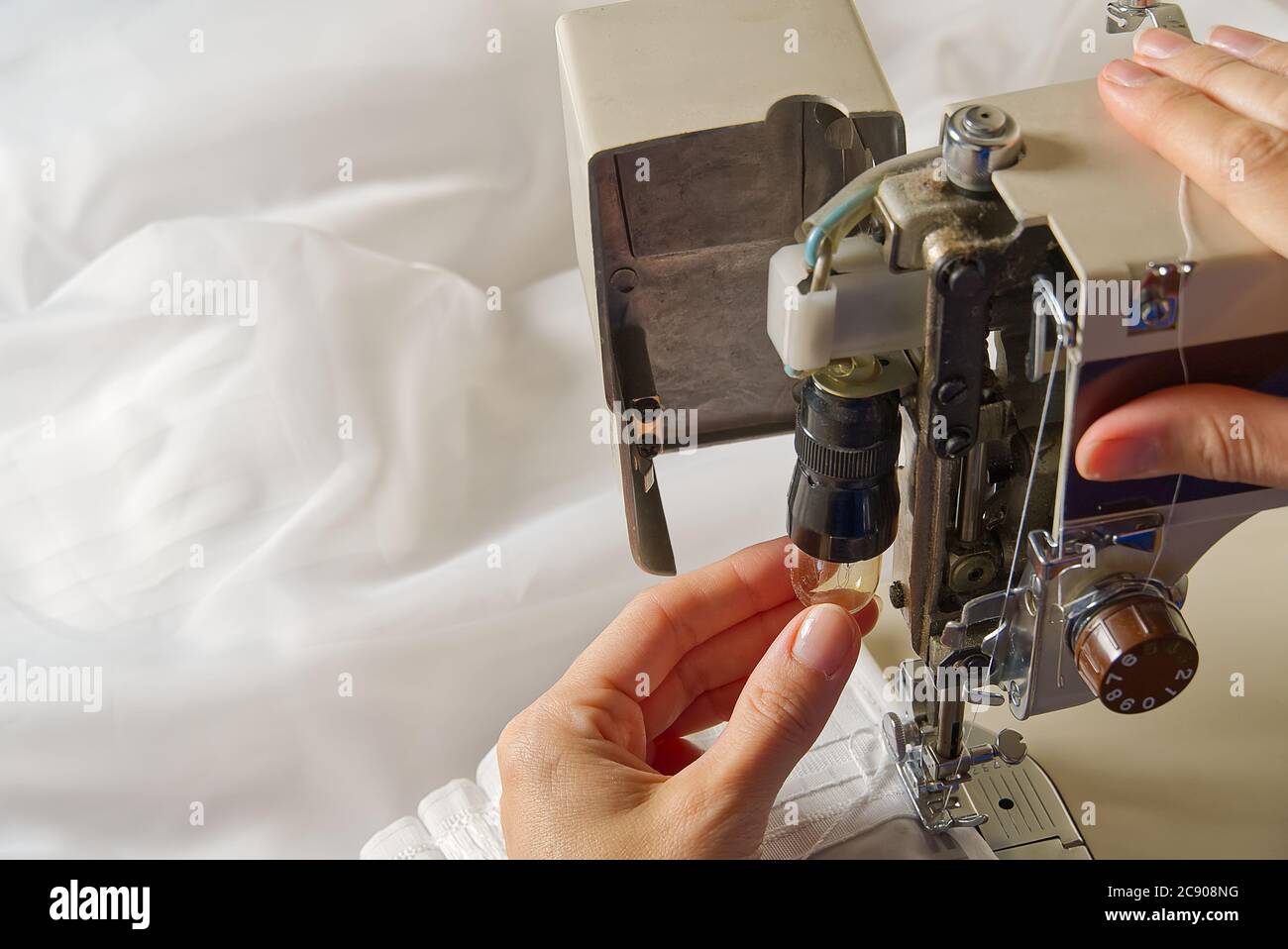 Woman's hands setting sewing machine. worker changing bulb in sewing machine. Stock Photo