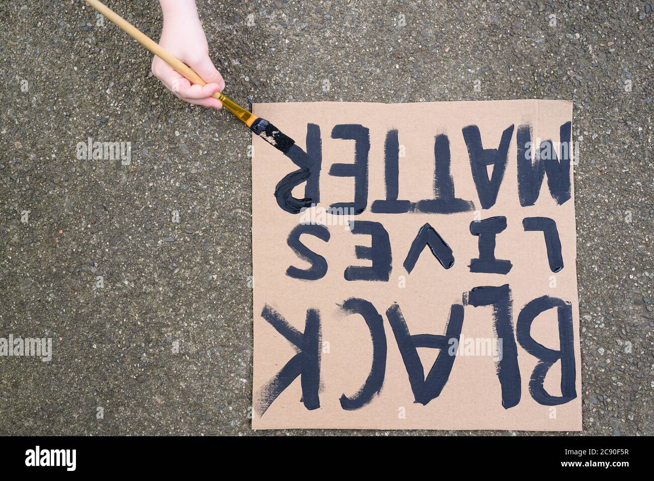 Woman's hand painting Black Lives Matter sign on cardboard Stock Photo