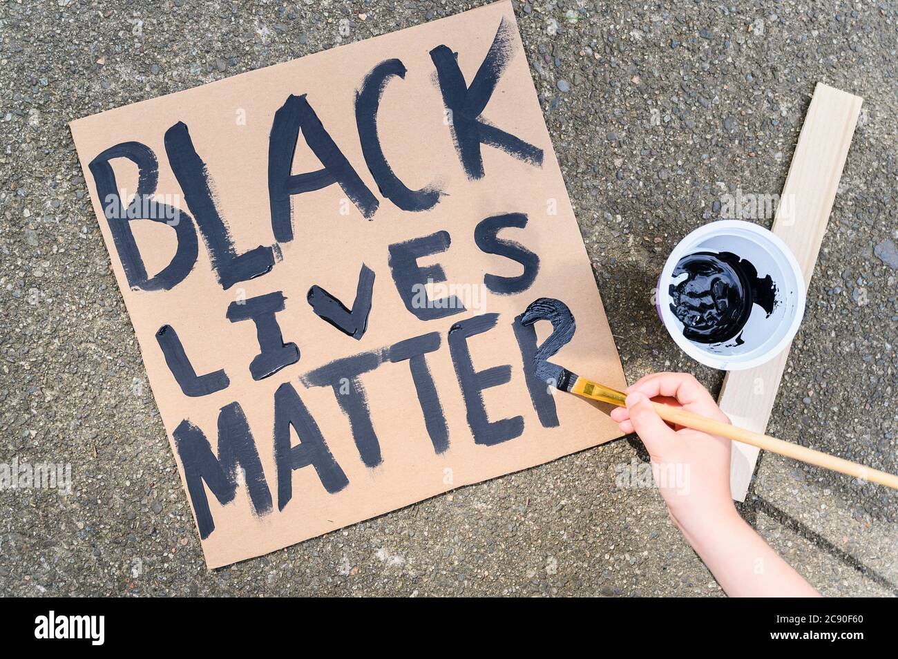 Woman's hand painting Black Lives Matter sign on cardboard Stock Photo