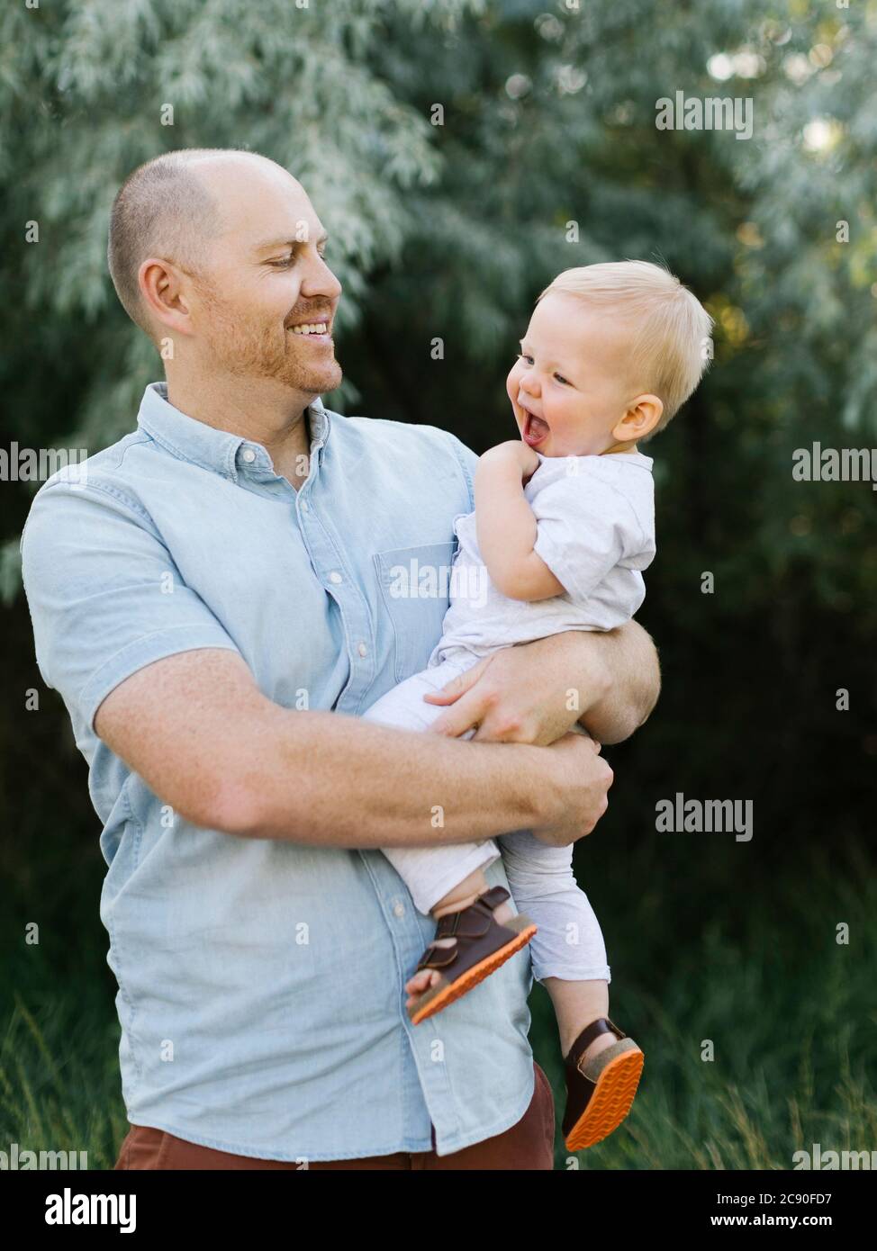 Outdoor portrait of father carrying baby son Stock Photo
