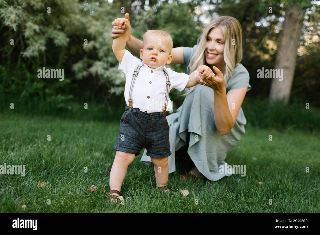 Mother with baby son learning to walk in park Stock Photo