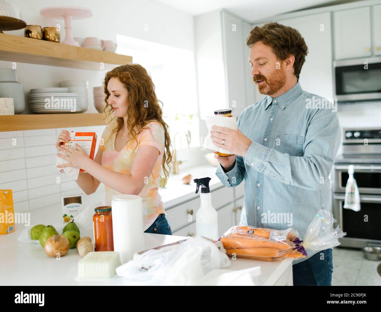 Man and woman cleaning groceries in kitchen Stock Photo