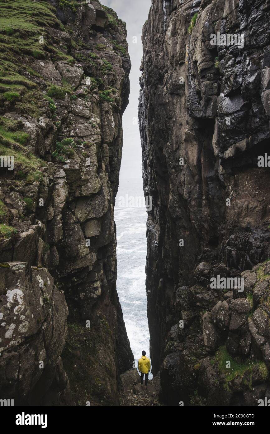 Denmark, Faroe Islands, Sorvagur, Man standing between two cliffs Stock Photo