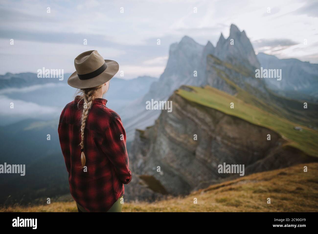 Italy, Dolomite Alps, Seceda mountain, Woman looking at scenic view of Seceda mountain in Dolomites at sunrise Stock Photo