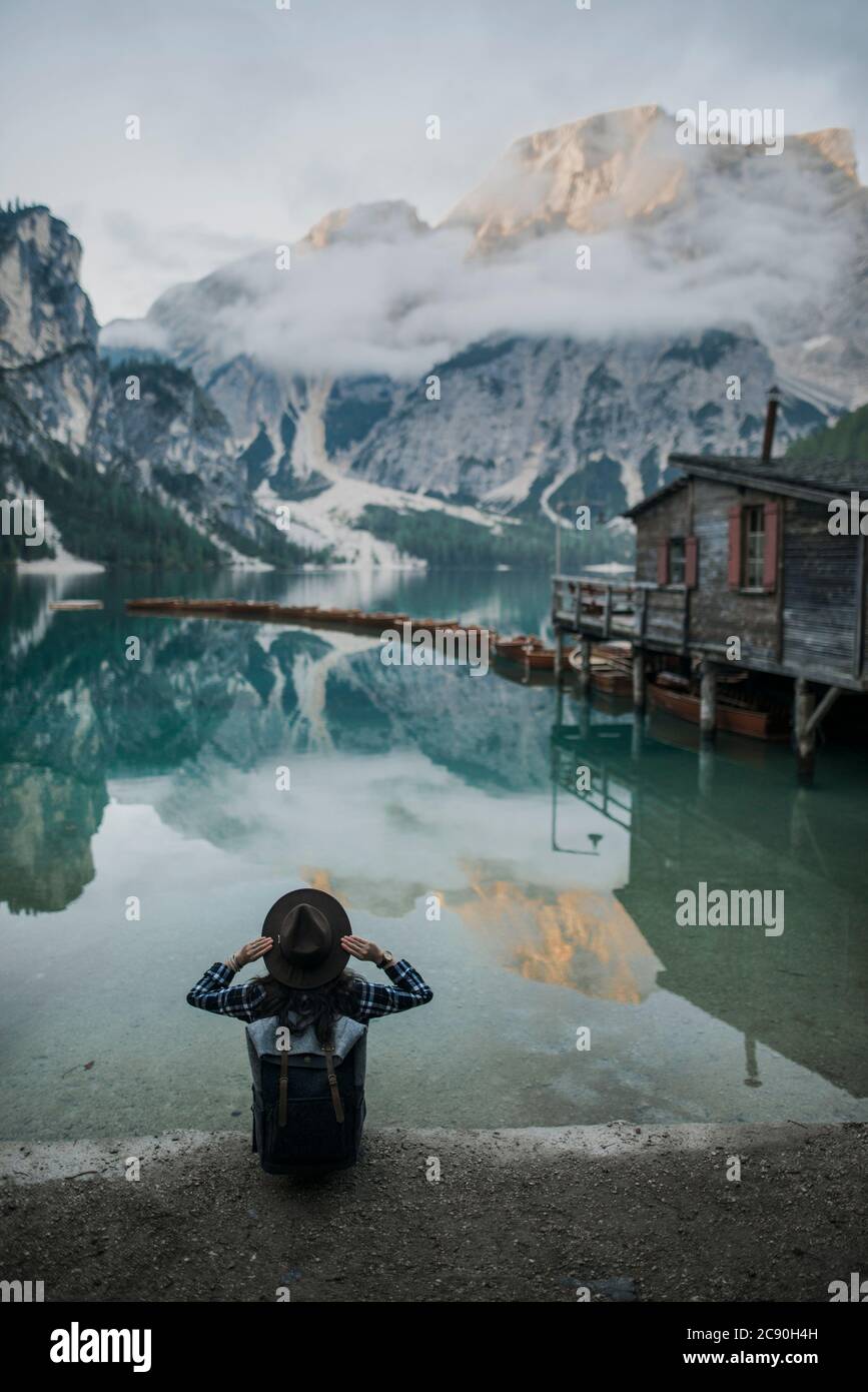 Italy, Woman sitting by Pragser Wildsee in Dolomites Stock Photo