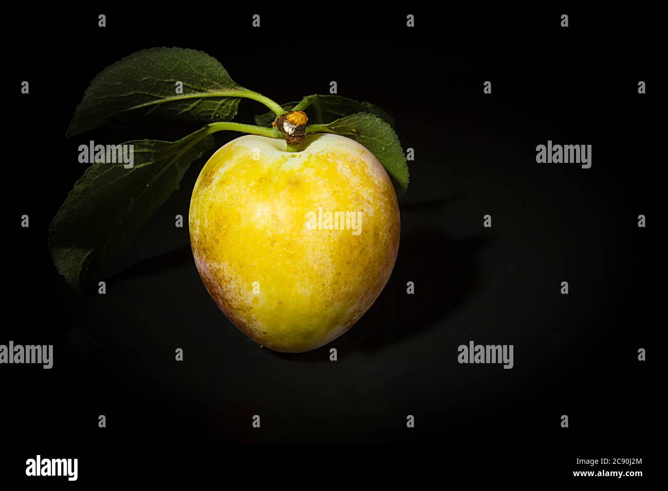 Ripe plums on a black reflective surface Stock Photo