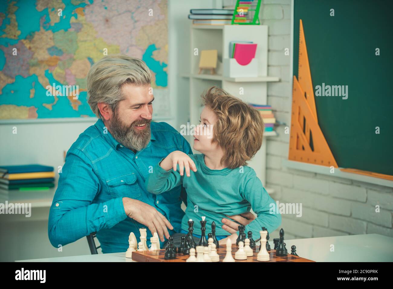 Teacher helping his pupil boy with chess on education class. Back to school. Father with son playing Chess at home. Stock Photo