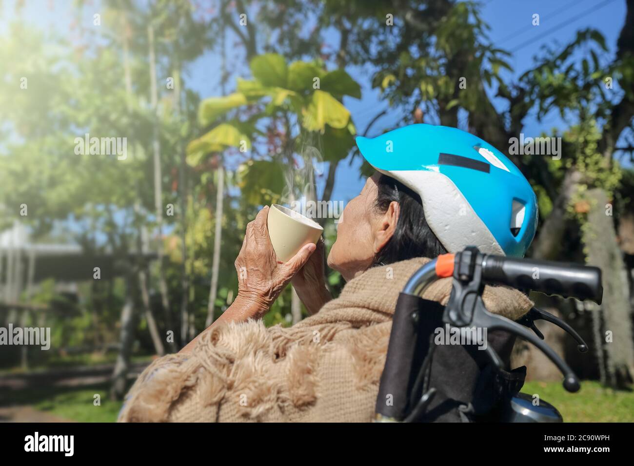 elderly woman in backyard puts on a safety head protection helmet from