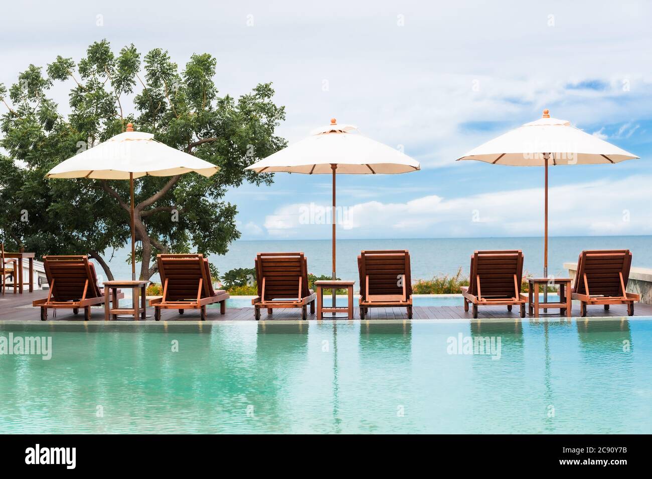 Umbrella and beach chairs beside the swimming pool with ocean view ...