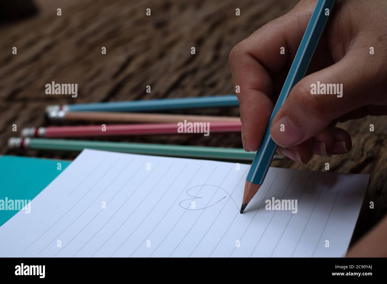 Hand holding pencil and book at wood desk background Stock Photo