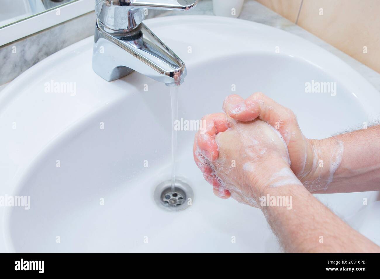 Man washing hands with soap under bathroom sink Stock Photo - Alamy
