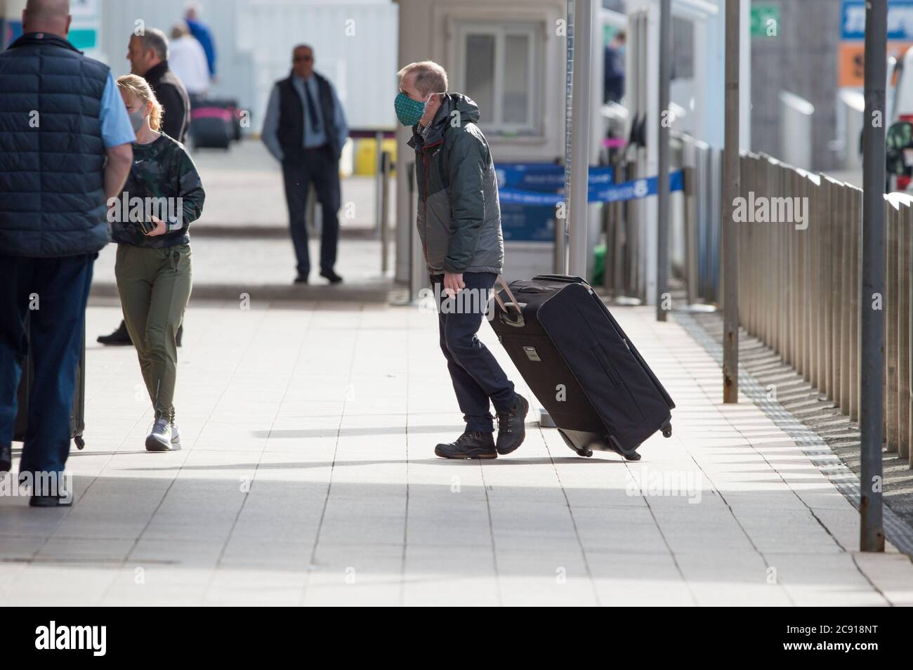 Glasgow, Scotland, UK. 28th July, 2020. Pictured: Passengers using Glasgow Airport seen carrying their luggage whilst wearing face masks. Today, Jet2 Holidays cancels all flights to Tenerife, Fuerteventura, Gran Canaria, Lanzarote, Majorca, Menorca and Ibiza after Foreign Office advised against non-essential travel to the islands. Jet2 planes now stand on the tarmac at Glasgow. Jet2 have advised passengers due to travel not to go to Scottish airports as their flights have been cancelled. Credit: Colin Fisher/Alamy Live News Stock Photo