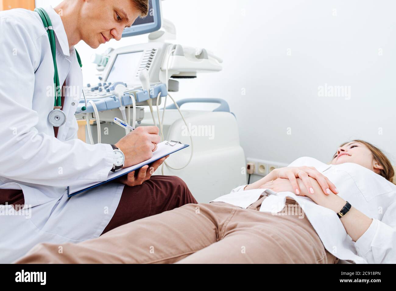 Attentive doctor chatting with young female patient on examination couch Stock Photo Alamy
