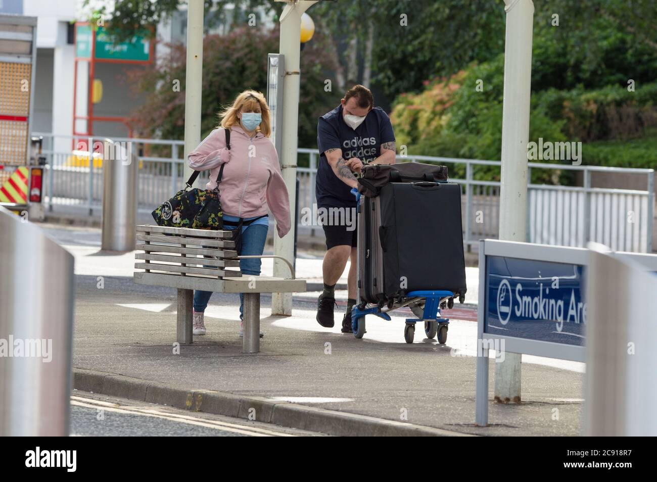 Glasgow, Scotland, UK. 28th July, 2020. Pictured: Passengers using Glasgow Airport seen carrying their luggage whilst wearing face masks. Today, Jet2 Holidays cancels all flights to Tenerife, Fuerteventura, Gran Canaria, Lanzarote, Majorca, Menorca and Ibiza after Foreign Office advised against non-essential travel to the islands. Jet2 planes now stand on the tarmac at Glasgow. Jet2 have advised passengers due to travel not to go to Scottish airports as their flights have been cancelled. Credit: Colin Fisher/Alamy Live News Stock Photo