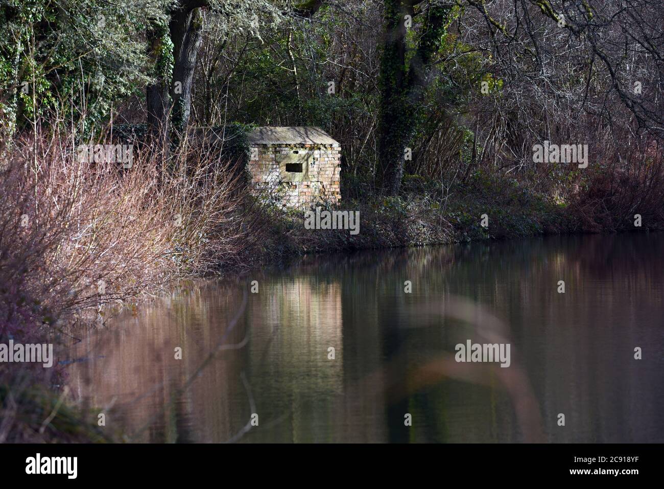 An old military structure is reflected in the still waters of the beautiful Basingstoke Canal in Hampshire, in this photo taken on a mild winter day Stock Photo