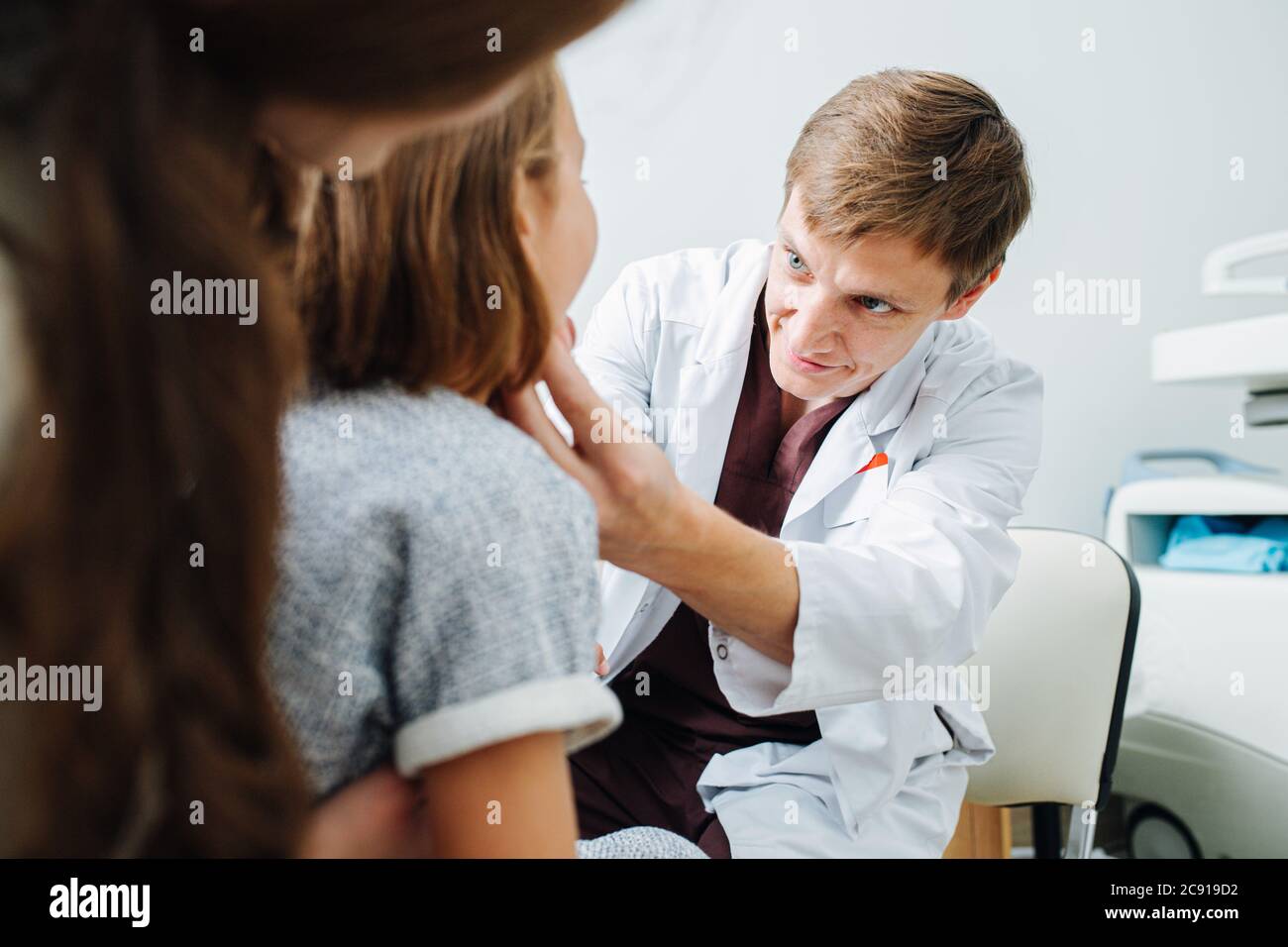 Little girl in being examined by friendly pediatrician, sitting on mom's lap Stock Photo