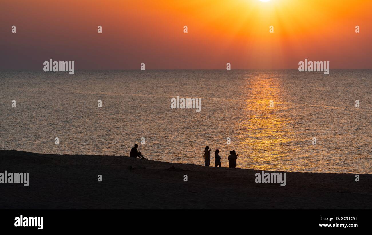 Silhouettes of people on beach at sunset Stock Photo - Alamy