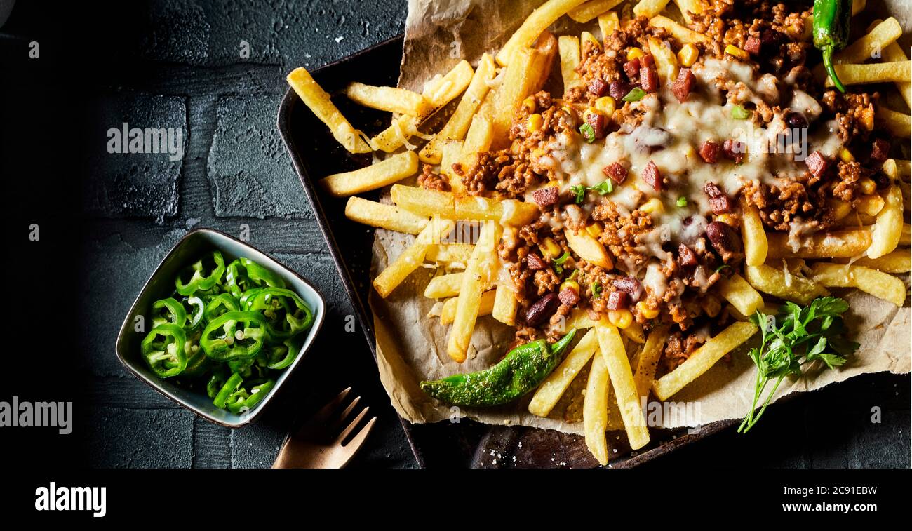 Close up on savory mince, cheese and potato fries seasoned with hot