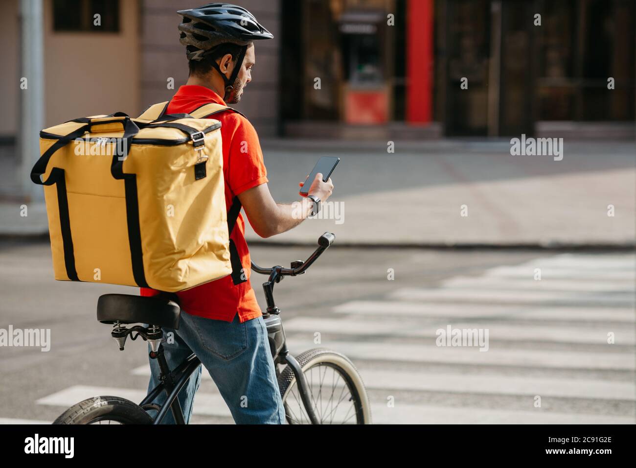 Delivery man on bicycle. Guy with backpack and helmet stopped at ...