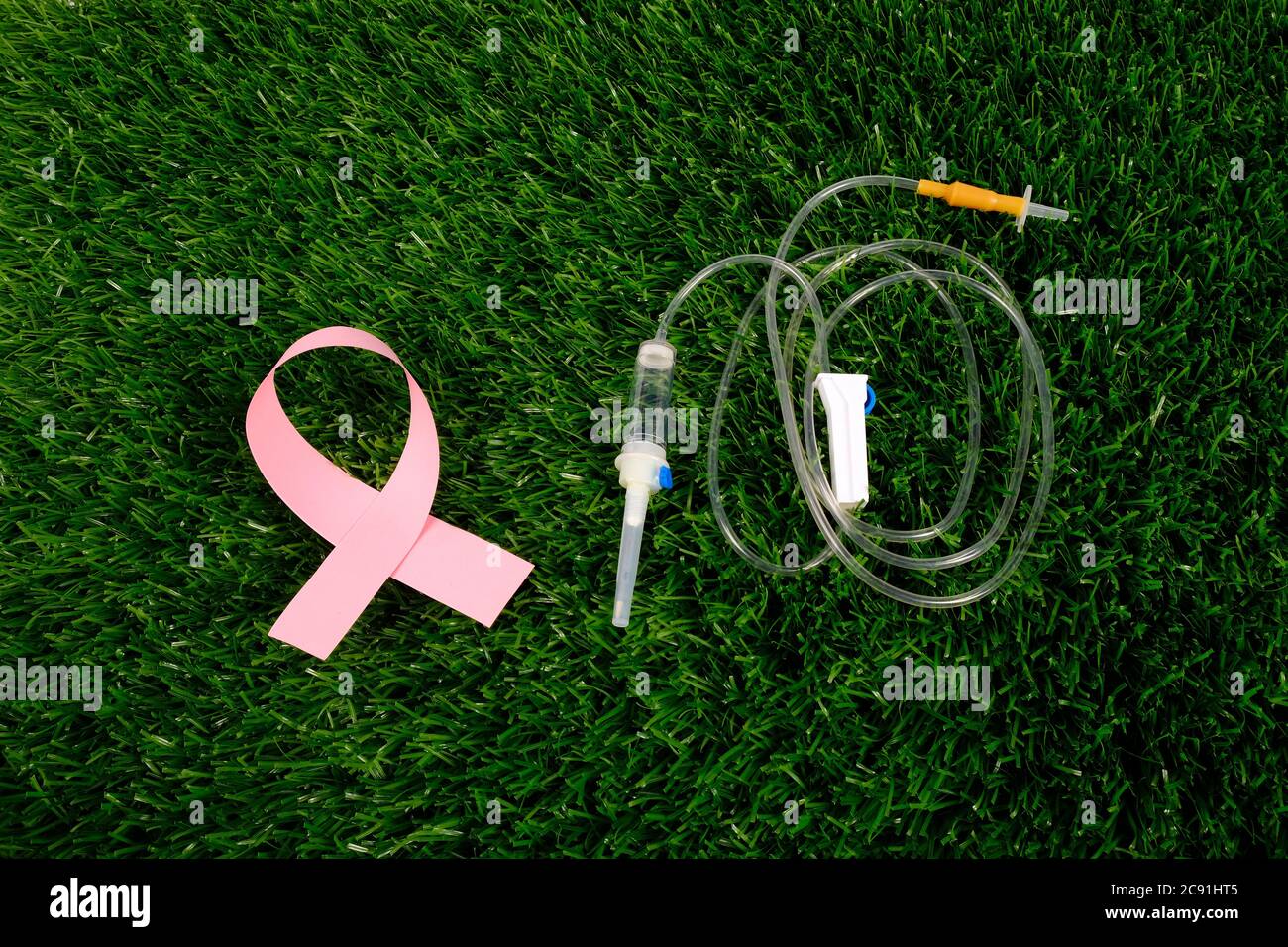 cancer fighting symbol. pink ribbon and dropper on green background top view, cancer awareness concept. Stock Photo