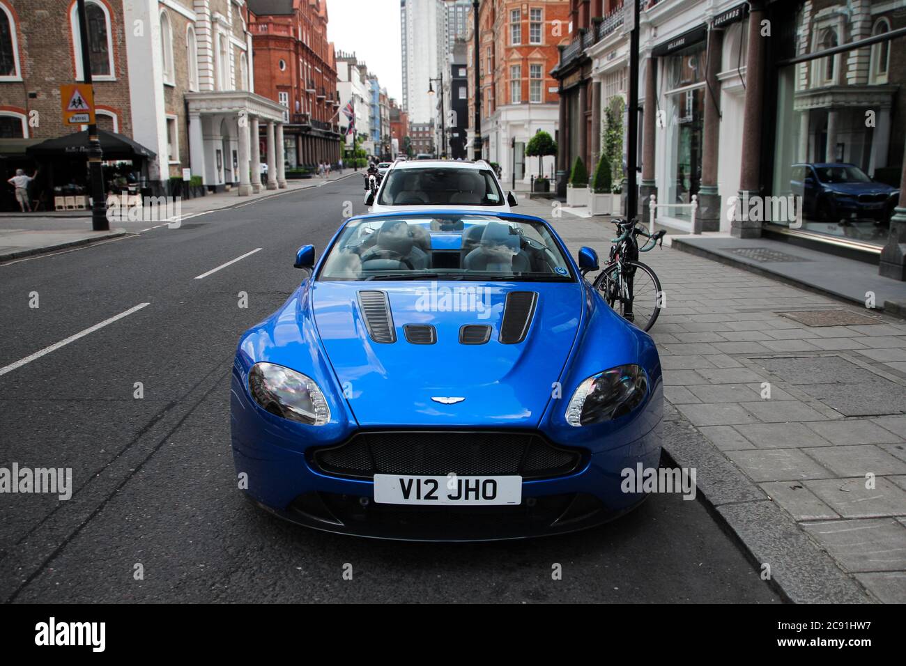 Blue Aston Martin V12 Vantage Volante modern supercar parked on a street of Mayfair area of Central London. Stock Photo