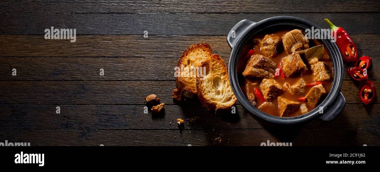 Pot if tasty German ragout with toasted baguette and chili peppers on a ...